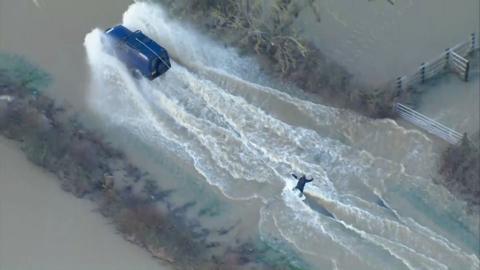 A man wakeboarding on a flooded road in Leicestershire