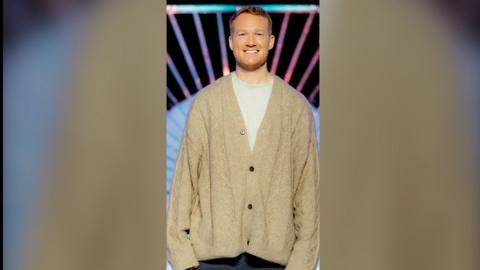 Greg Rutherford on the Drag Race UK set wearing an oversized cardigan
