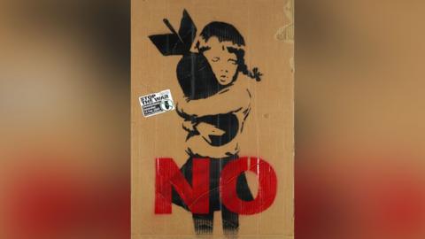A Banksy placard showing a child hugging a bomb with the word "No" in red writing across the bottom.