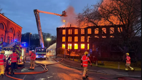 building on fire with lots of firefighters and crane 