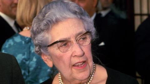 Crime writer Agatha Christie, wearing horn rimmed glasses and a pearl necklace, at an unknown event in July 1967.