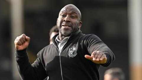 Port Vale manager Darren Moore is about the throw an air punch in celebration on the touchline