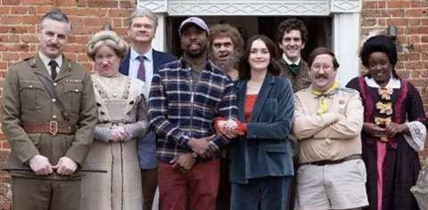 Cast photo of the characters from the show outside Button House, in costume