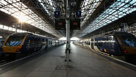 Two trains parked at a platform at Manchester Piccadilly station.
