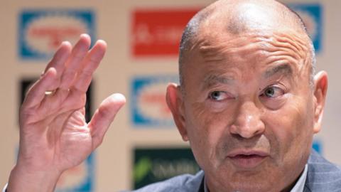 Eddie Jones raises his hand during a media conference
