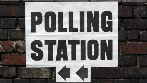 Polling station sign on brick wall