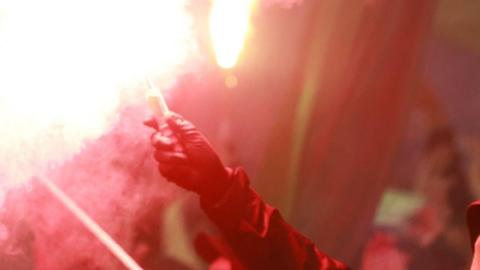 A person wearing a glove holds up a red flare (stock image).