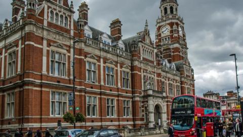 Croydon town hall, a red brick building with flags outside and a red bus at a stop.
