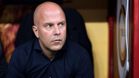 Arne Slot looks on thoughtfully from seat in dugout