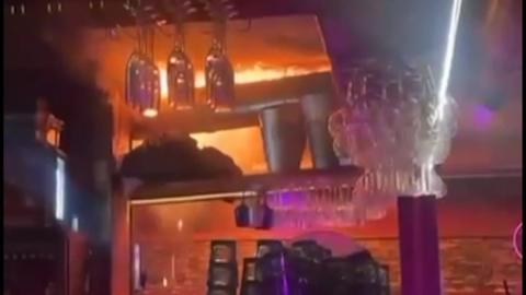 Flames on the ceiling of a dark bar