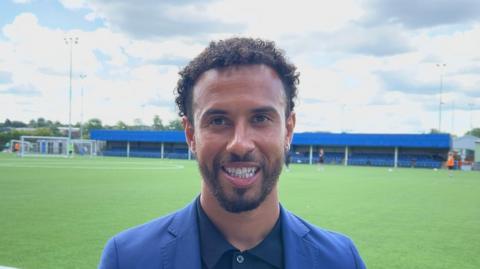 Sam Cox with football ground behind him