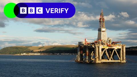 Offshore rig in the sea near a coastal village at dusk