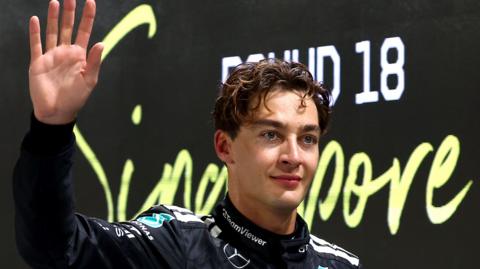 Mercedes' George Russell waves in celebration after taking pole position for the Singapore Grand Prix
