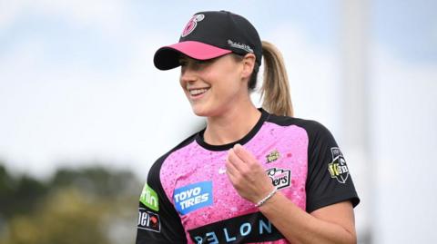 Ellyse Perry smiles in a Hobart Hurricanes shirt