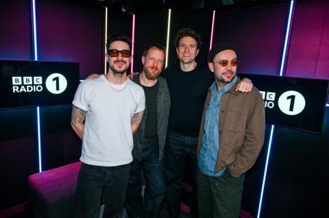 The three members of Mumford and Sons stand with Greg James in the Radio 1 studio