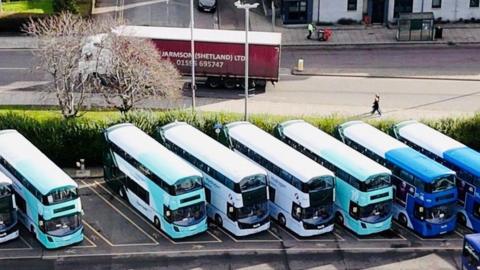 Several hydrogen buses lined up in parking bays, taken from the air.