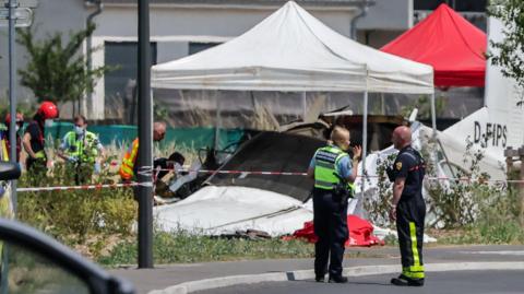 Emergency service workers speak to each other as the attend a light aircraft crash site