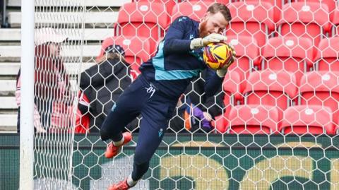 Viktor Johansson dives to catch a ball while warming up for Stoke