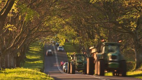 Tractors and cars on road