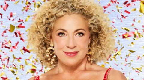 Alex Kingston in tassled red dress with red and gold confetti falling behind her in a Strictly promotional photo