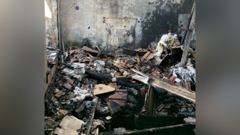 The inside of a building damaged by a fire, with burnt rubble and debris on the ground