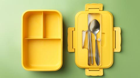Yellow lunchbox with three compartments and spoon and chopsticks