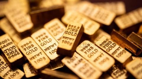 A pile of gold bars. They are all engraved with "999.9 Fine Gold netwt 100g".