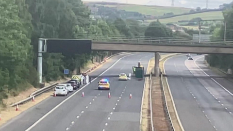 A drone shot of a section of empty motorway, with police vehicles to the left