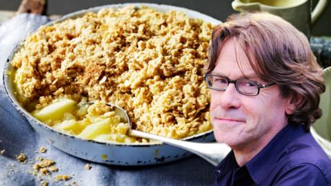 An apple crumble topped with oats, with a photo of Nigel Slater edited in to the right side of the frame.