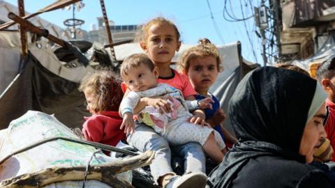 File photo showing Palestinian children sitting on top of their family's belongings as they flee areas north of Gaza City, in the northern Gaza Strip (12 October 2024)