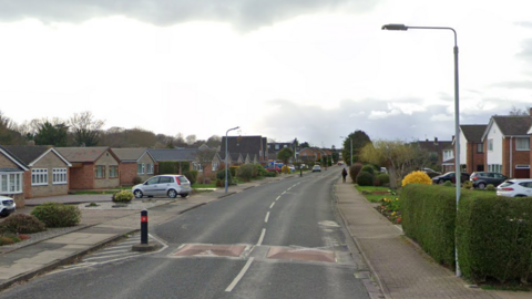 A residential road with bungalows on one side of the road and detached homes on the other, and traffic calming measures installed