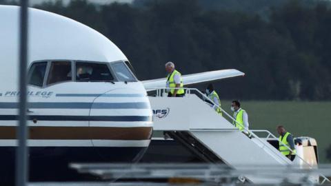 Members of staff board a plane first earmarked to transport migrants to Rwanda, at Boscombe Down airbase in Wiltshire.