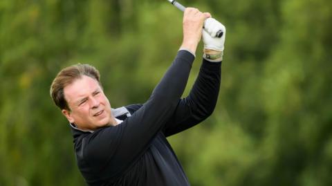 Amateur golfer Allan Harrison watches his ball after hitting a shot