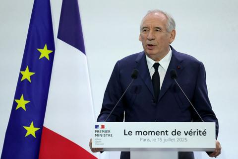 Francois Bayrou stands in front of a lectern reading "The moment of truth". Behind him are a French and an EU flag