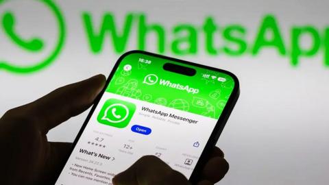 Someone logging into WhatsApp on a phone, with a WhatsApp logo visible in the background