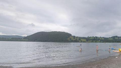 A general view of the shore at Ullswater with children playing in the water.