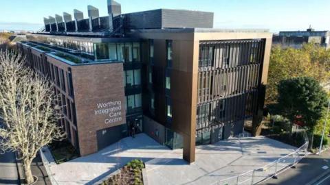 An aerial shot of the Worthing integrated care centre. It shows a brown building with a patio and trees in front.