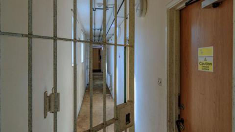 An open gate and a door with "caution: uneven surface" at Campsfield House