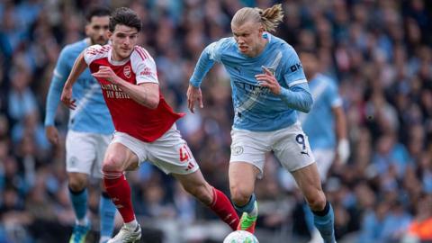 Declan Rice and Erling Haaland run for the ball