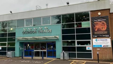 The Octagon Theatre building in Yeovil. It has a blue entrance and glass walls along the front.