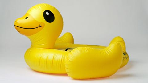 An inflatable yellow duck against a white background