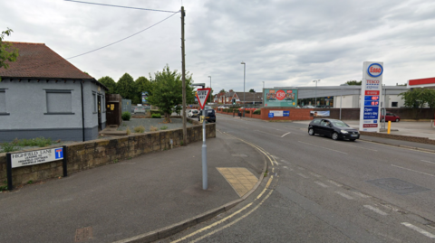 Junction of Highfield Lane and Nottingham Road in Chaddesden with Esso petrol station in the background and black car travelling along the road