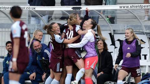 Four Aston Villa players hug in front of the dugout