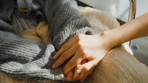 A close-up file picture of two people's hands, with a hand seen to be comforting the other person's hands