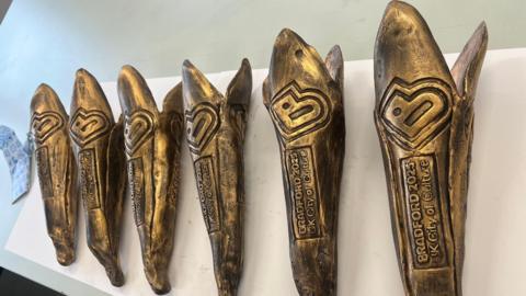 Six gold-coloured ceramic batons with Bradford 2025 UK City of Culture stamped on them. They look a little like an Olympic torch.