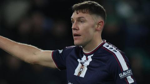 A photo of Paul Digby, wearing his dark blue Dundee United kit, directing his teammates with his finger outstretched while playing Hibernian in November