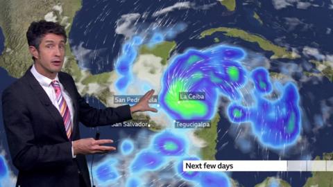 Chris Fawkes standing in front of a weather map of Honduras