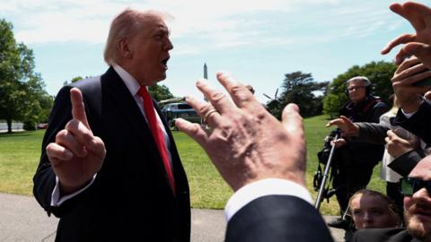 Trump talking to reporters whil holding finger up to camera