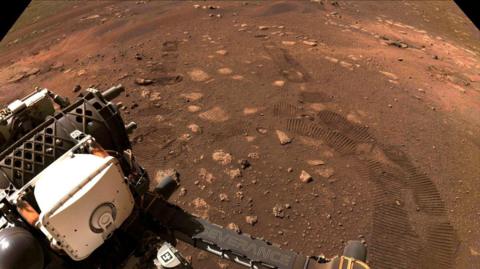 Orange dust and rocks on Mars surface with white space rover. 