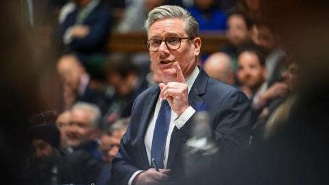 Starmer, framed by out-of-focus MPs, points as he speaks at the dispatch box in the House of Commons